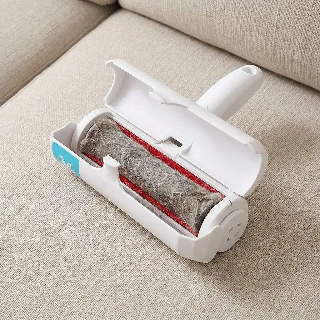 Pet hair removal tool on a couch with an open waste compartment showing a dense, compacted log of grey cat hair and dust. Pet hair removal tool on a couch with an open waste compartment showing a dense, compacted log of grey cat hair and dust.